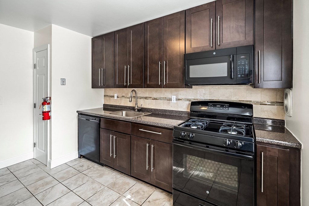 a kitchen with dark wood cabinets and a stove and a microwave