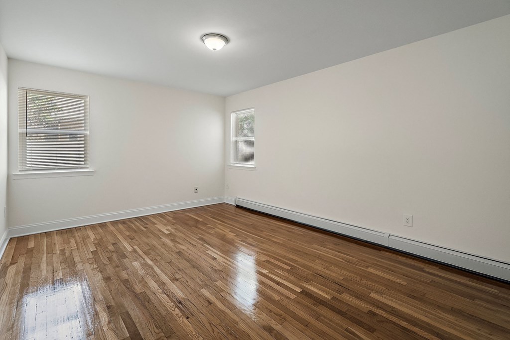 an empty living room with wood floors and white walls