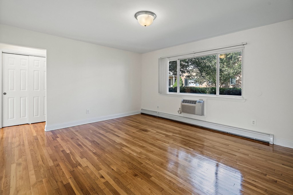 an empty living room with wood floors and a window