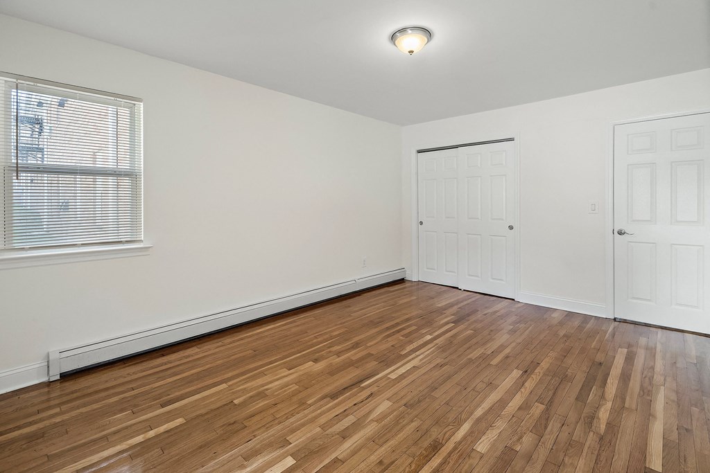 a living room with wood floors and white walls and a window