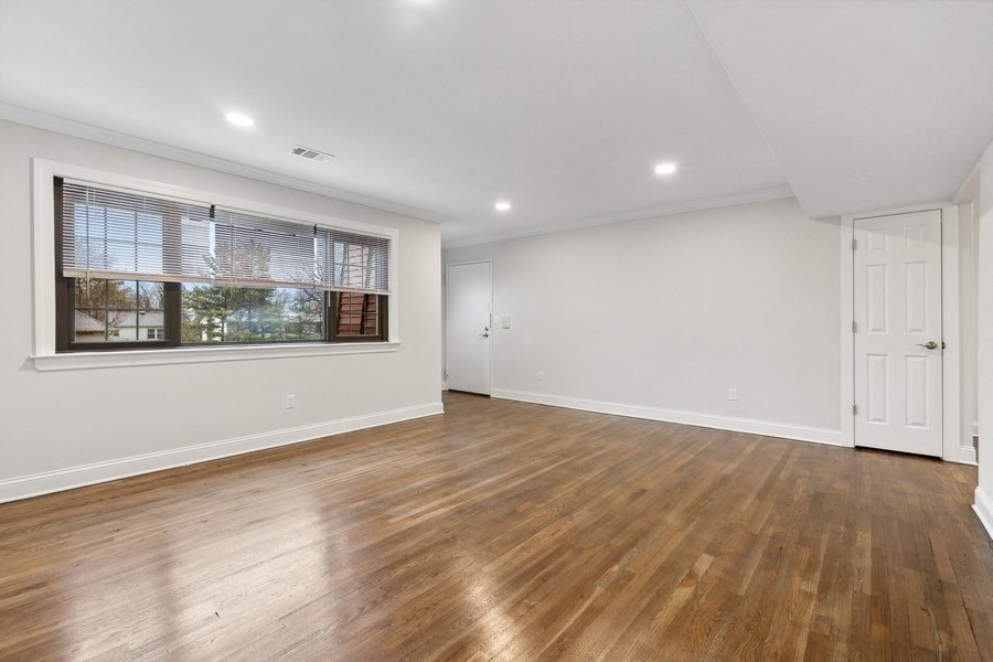 the living room is spacious and has a large window and hardwood floors
