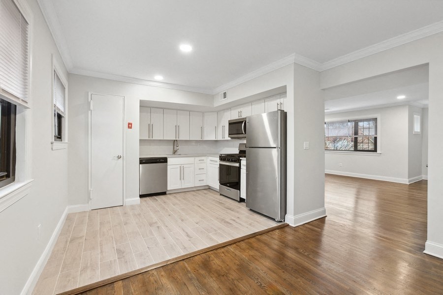 an empty living room with a kitchen with stainless steel appliances