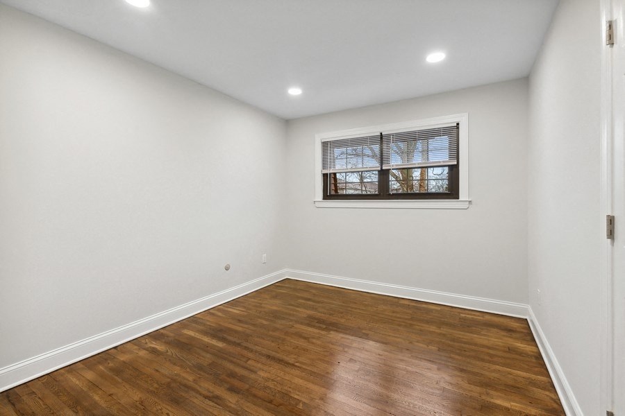 an empty room with white walls and wood flooring and a window