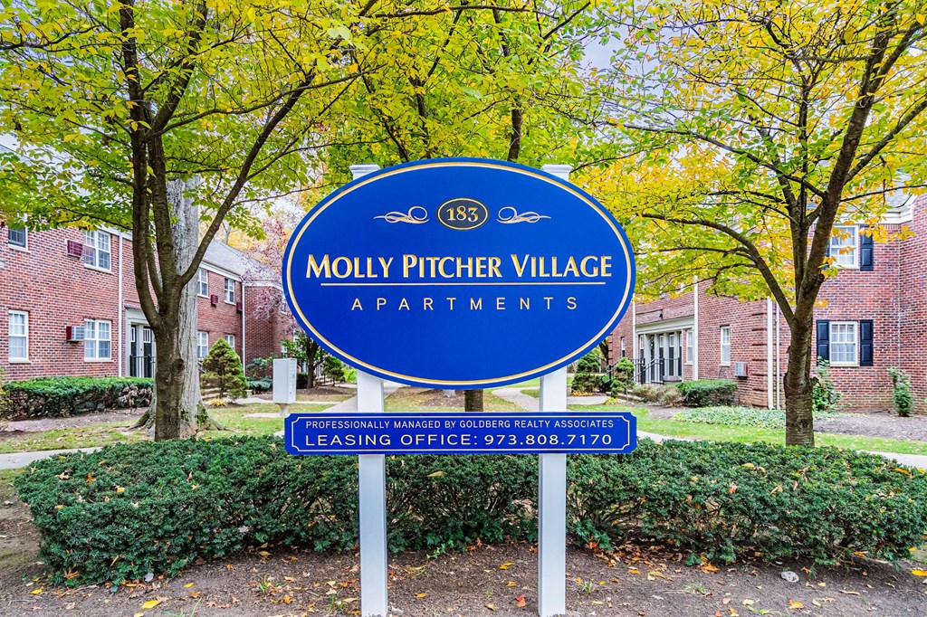 a sign village apartments in front of trees