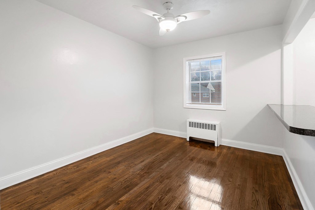 a bedroom with white walls and wood floors and a window