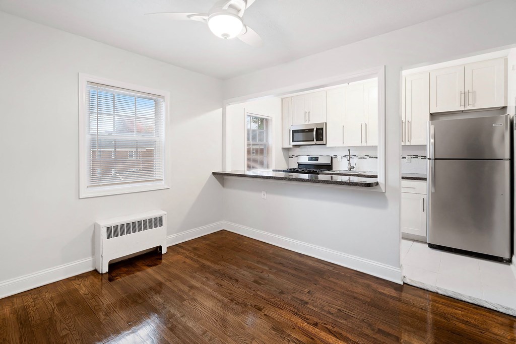 an empty kitchen with a stainless steel refrigerator and microwave