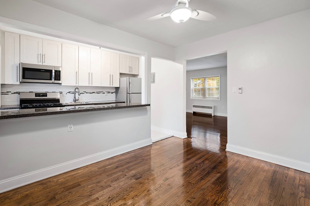 an empty kitchen and living room with white cabinets