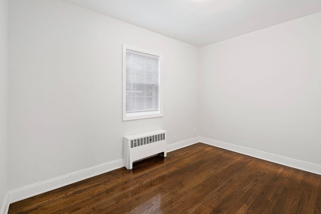 a room with white walls and wood floors and a window