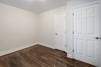 a bedroom with white walls and wood flooring and white doors
