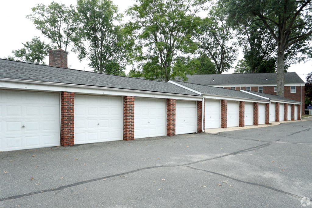 a row of garages with white doors and brick columns