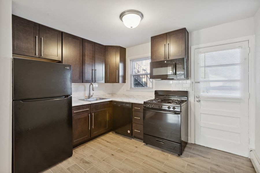 an empty kitchen with black appliances and wooden cabinets