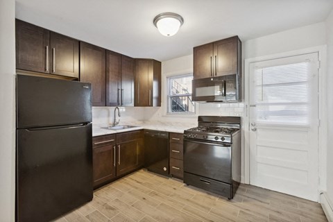 an empty kitchen with black appliances and wooden cabinets