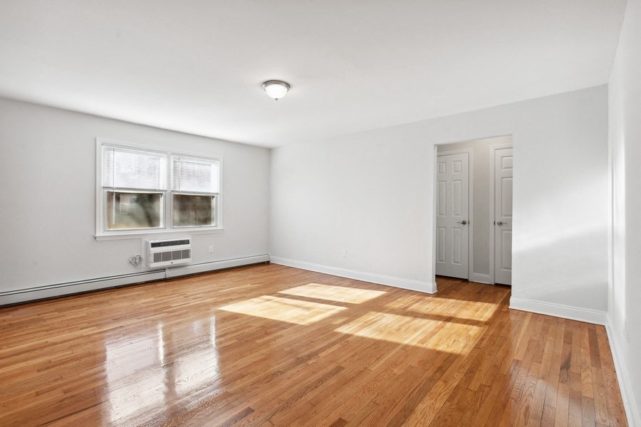 an empty living room with wood floors and white walls