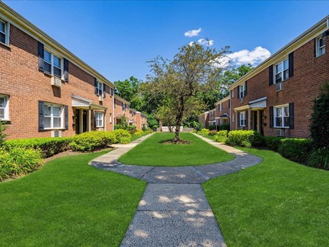 a walkway in the middle of a yard between two brick buildings