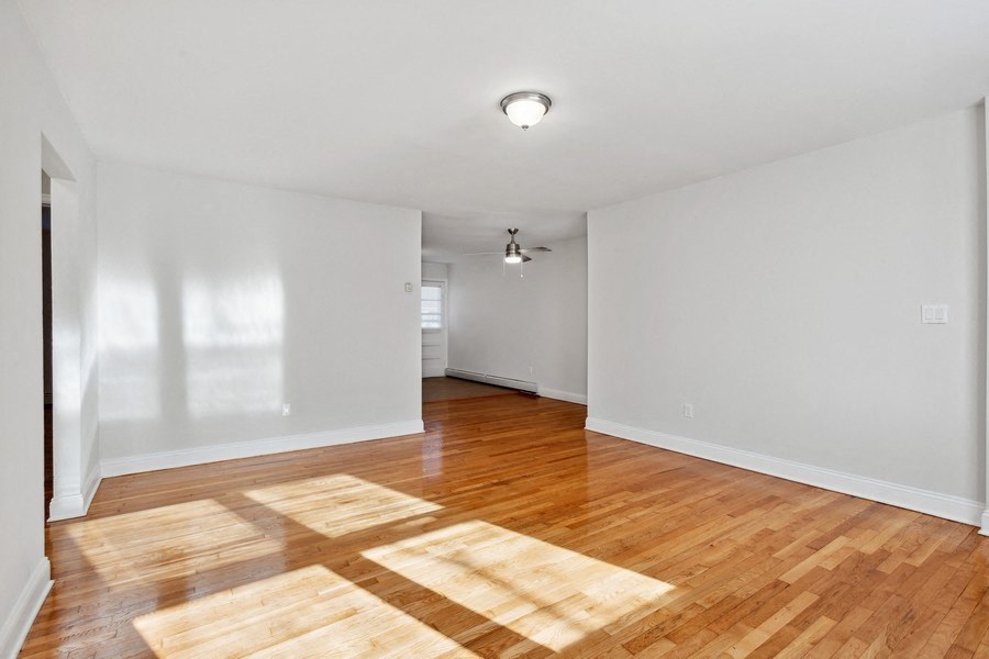 an empty living room with wood floors and white walls