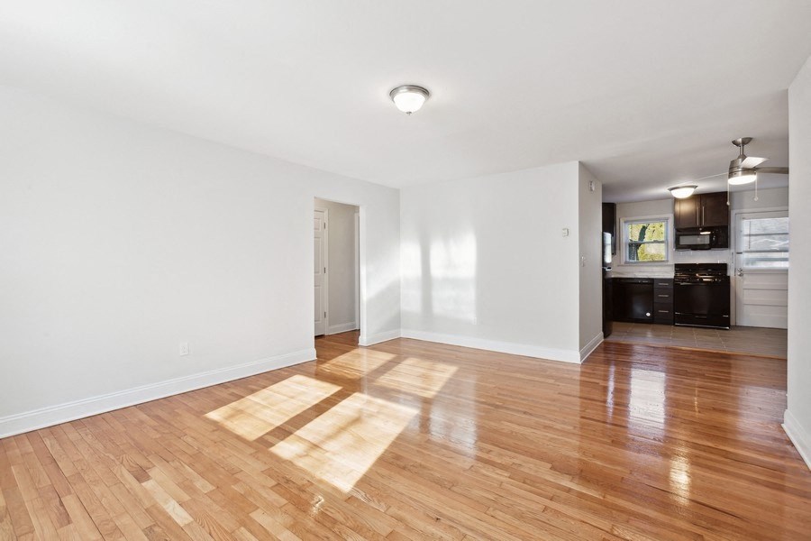 an empty living room with wood floors and a kitchen