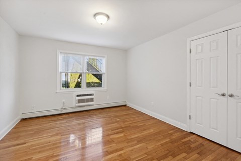 an empty bedroom with white walls and wood floors and a window