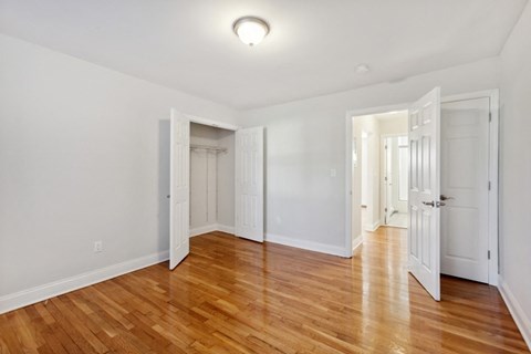 an empty living room with wood floors and white walls