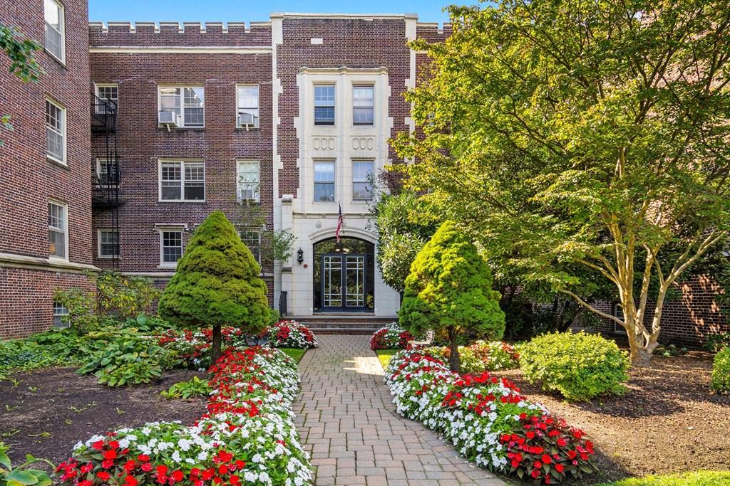 the front of a brick building with a garden in front of it