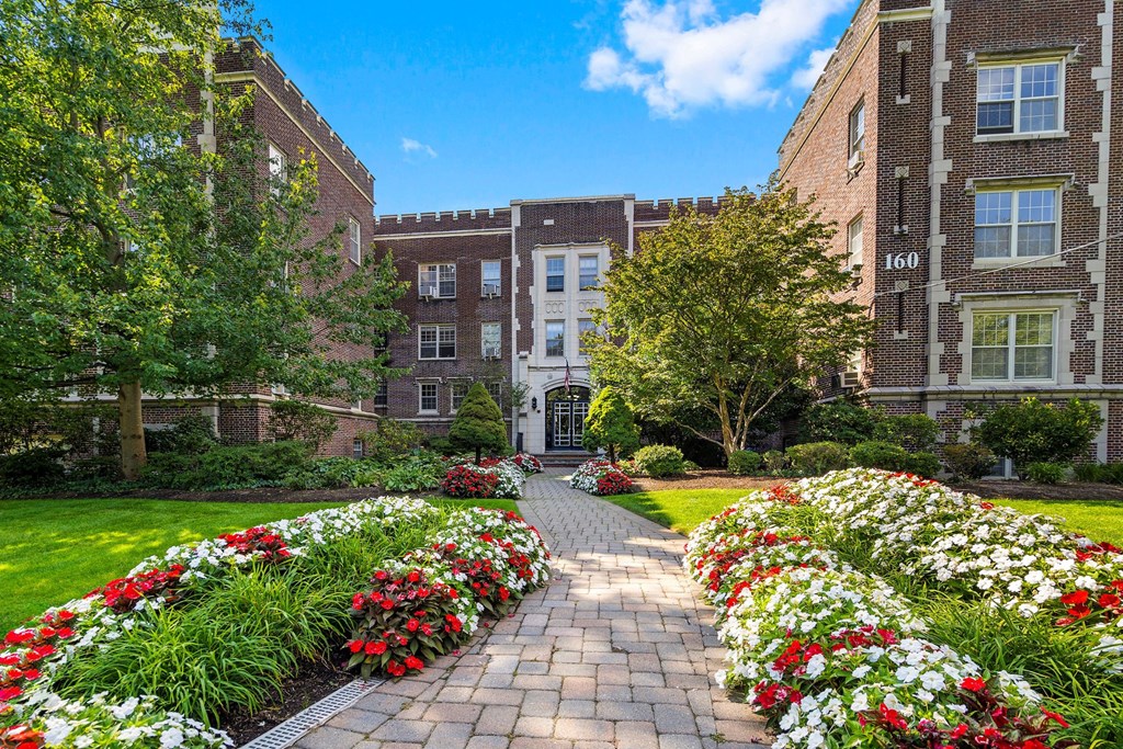 a brick walkway with colorful flowers in front of a building
