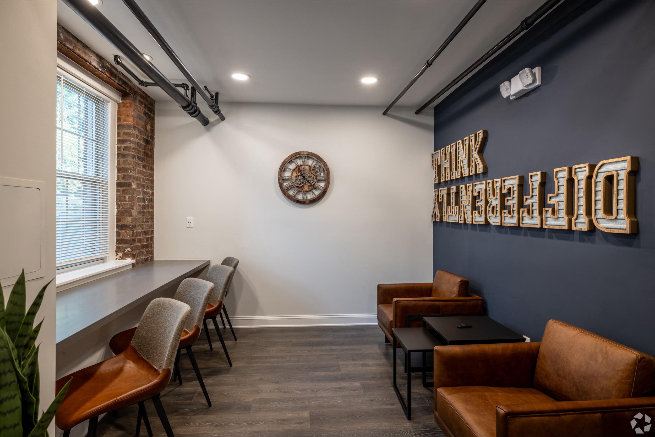 a lounge area with couches and chairs and a clock on the wall