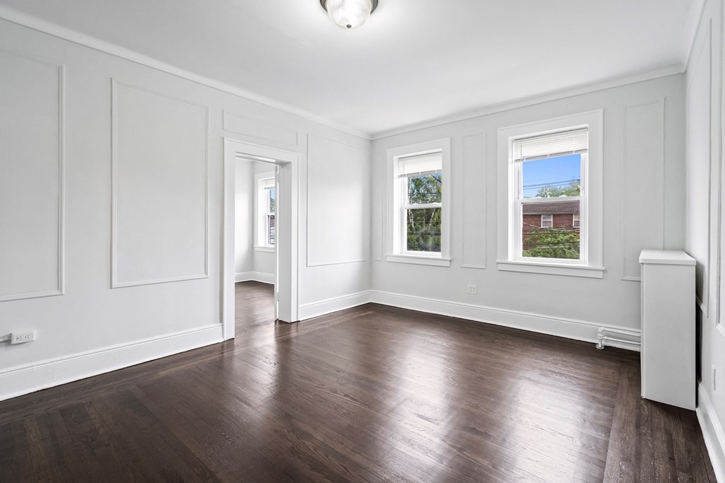 an empty living room with white walls and wood floors