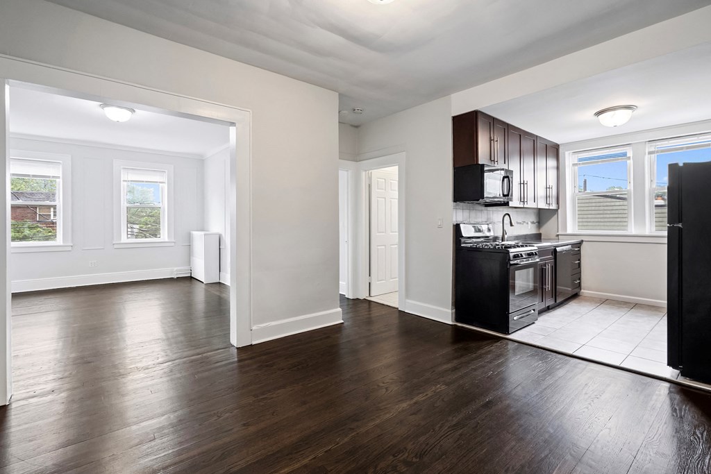 an empty kitchen and living room with wood flooring and a window