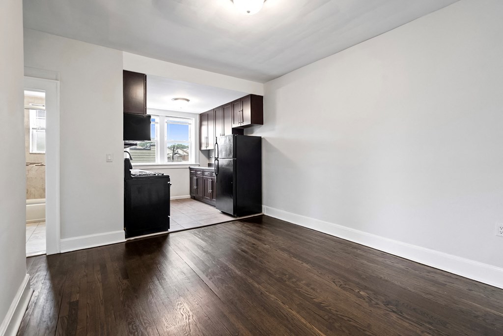 an empty living room and kitchen with hard wood flooring