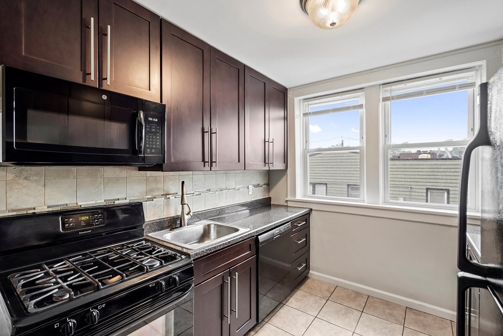 an empty kitchen with a sink and stove and a window