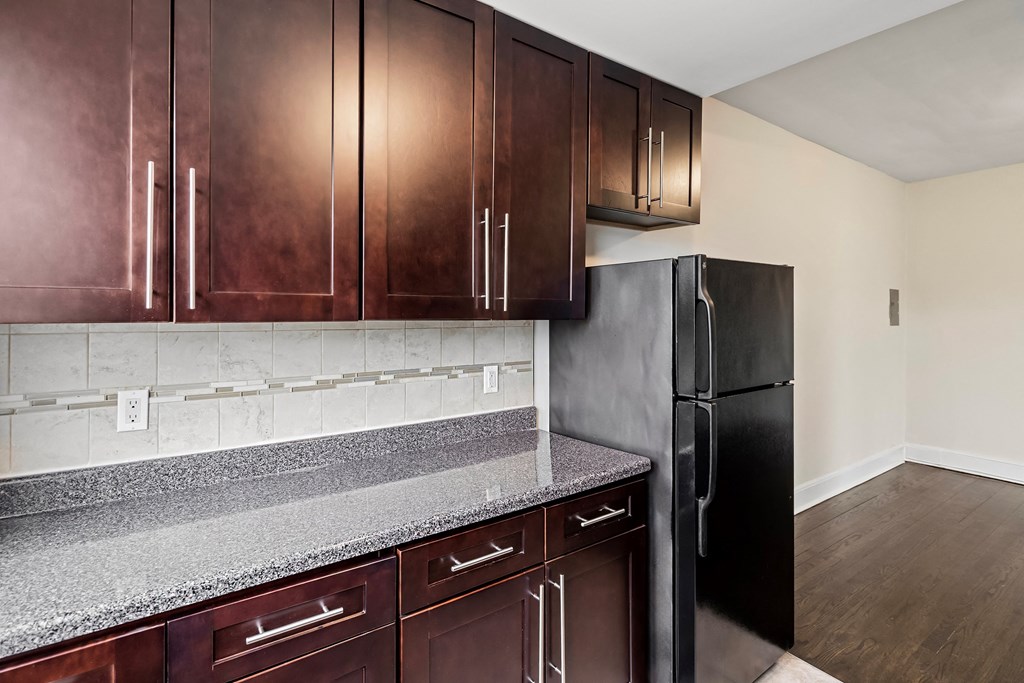 a kitchen with dark wood cabinets and granite counter tops and a black refrigerator