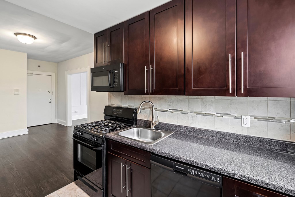 a kitchen with dark wood cabinets and granite counter tops and a sink