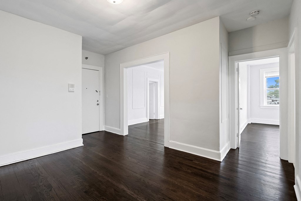 an empty living room with white walls and wood floors