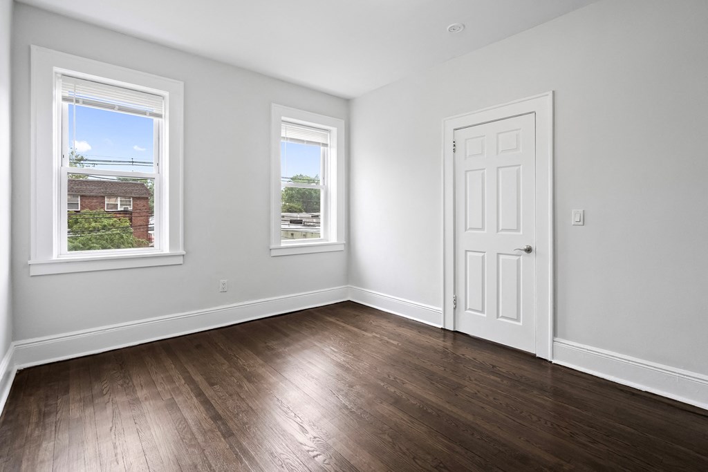 an empty room with a door and two windows