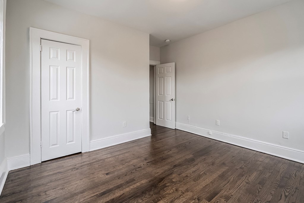 an empty living room with white walls and wood flooring