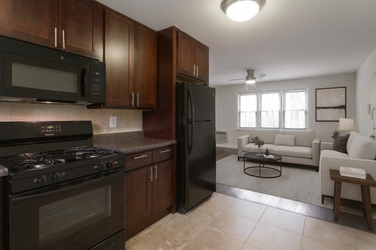 A kitchen with dark wood cabinets and black appliances.