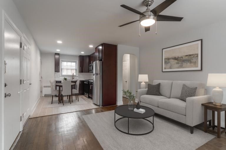 A living room with a grey couch, a black coffee table, and a ceiling fan.