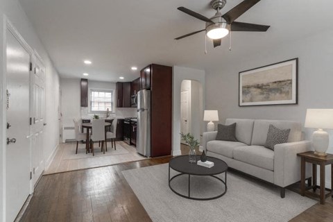 A living room with a grey couch, a black coffee table, and a ceiling fan.