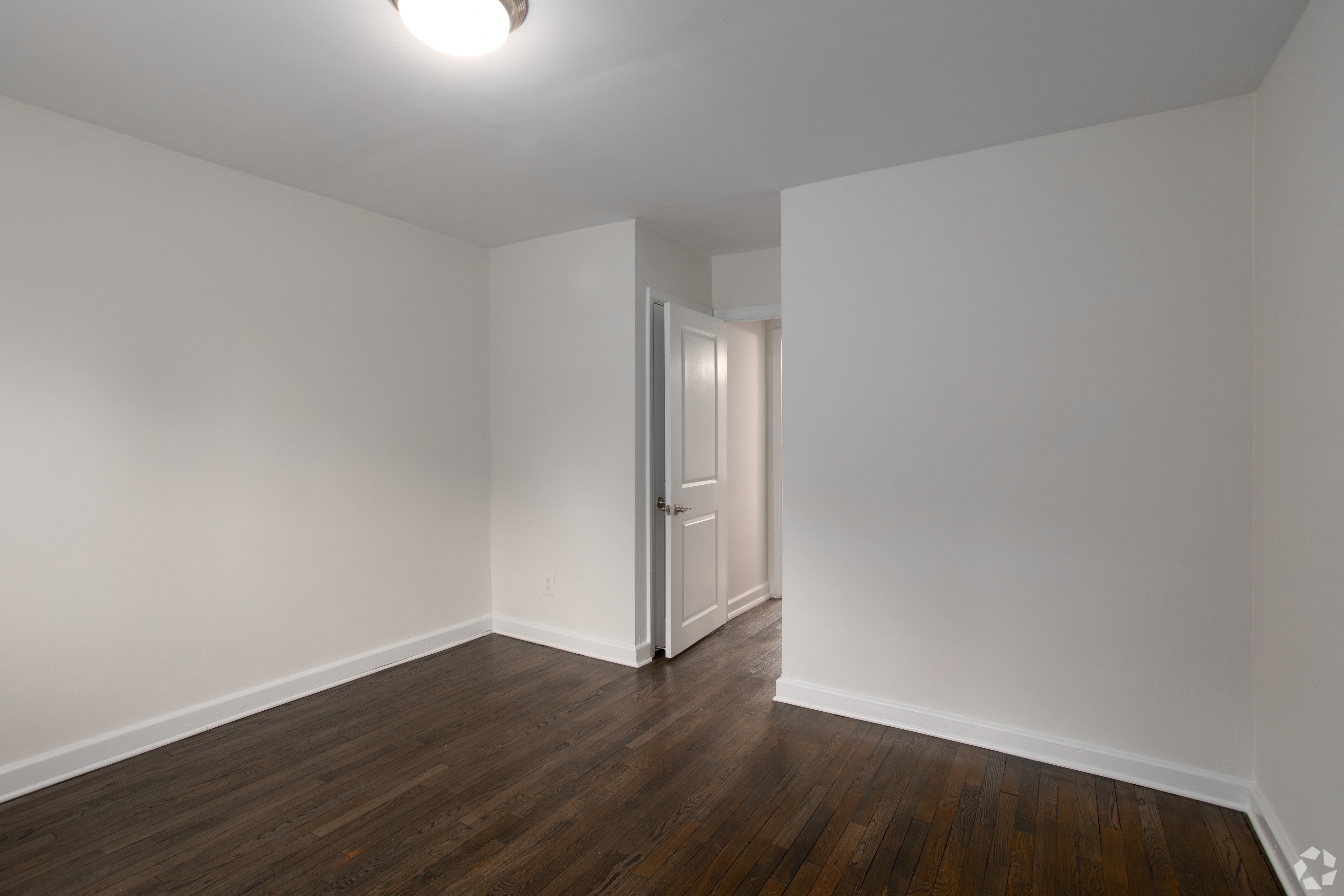 a bedroom with white walls and wood flooring and a closet