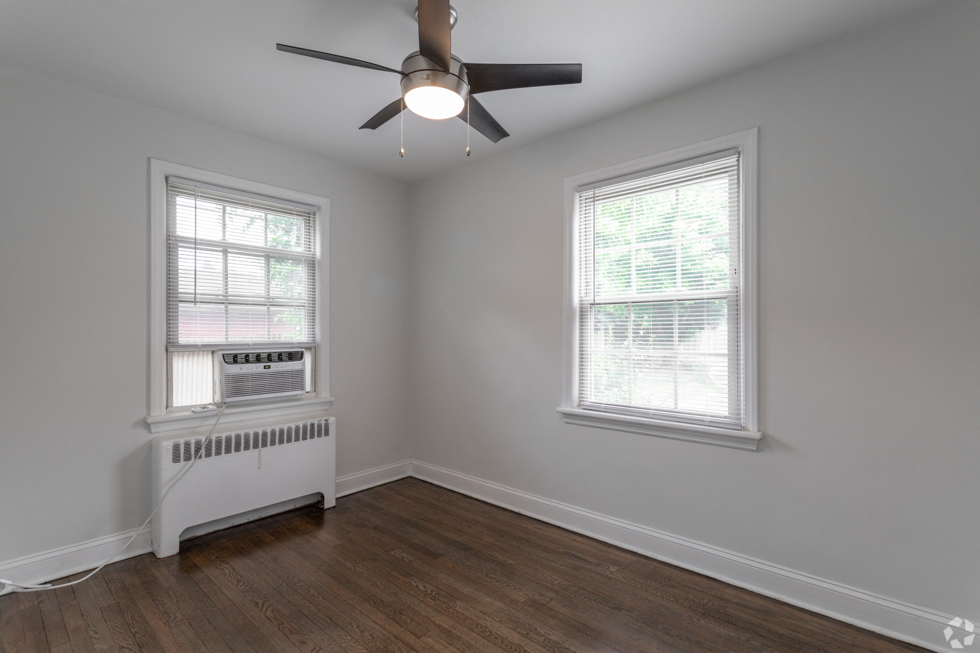 an empty room with a ceiling fan and two windows