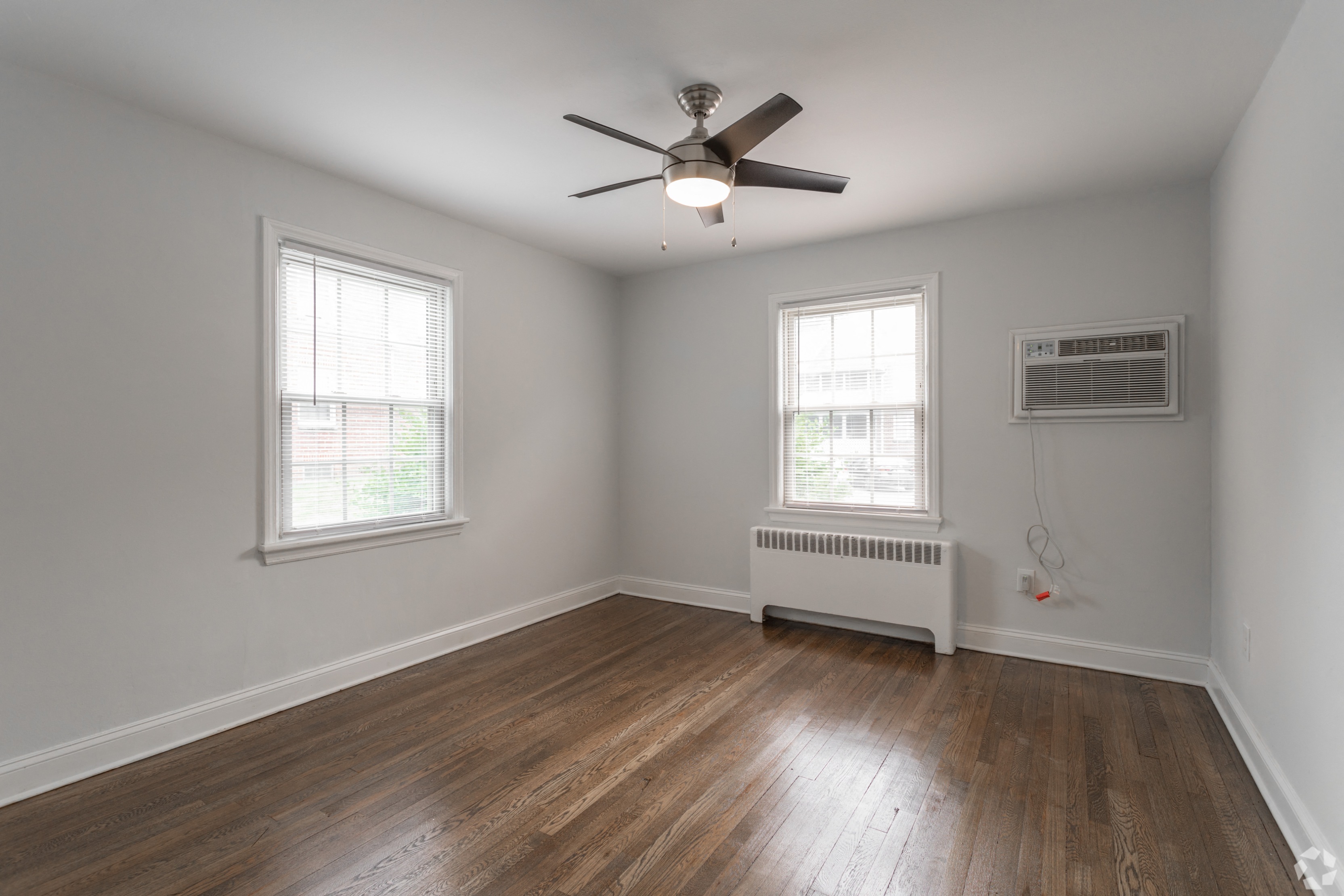 an empty living room with wood floors and a ceiling fan
