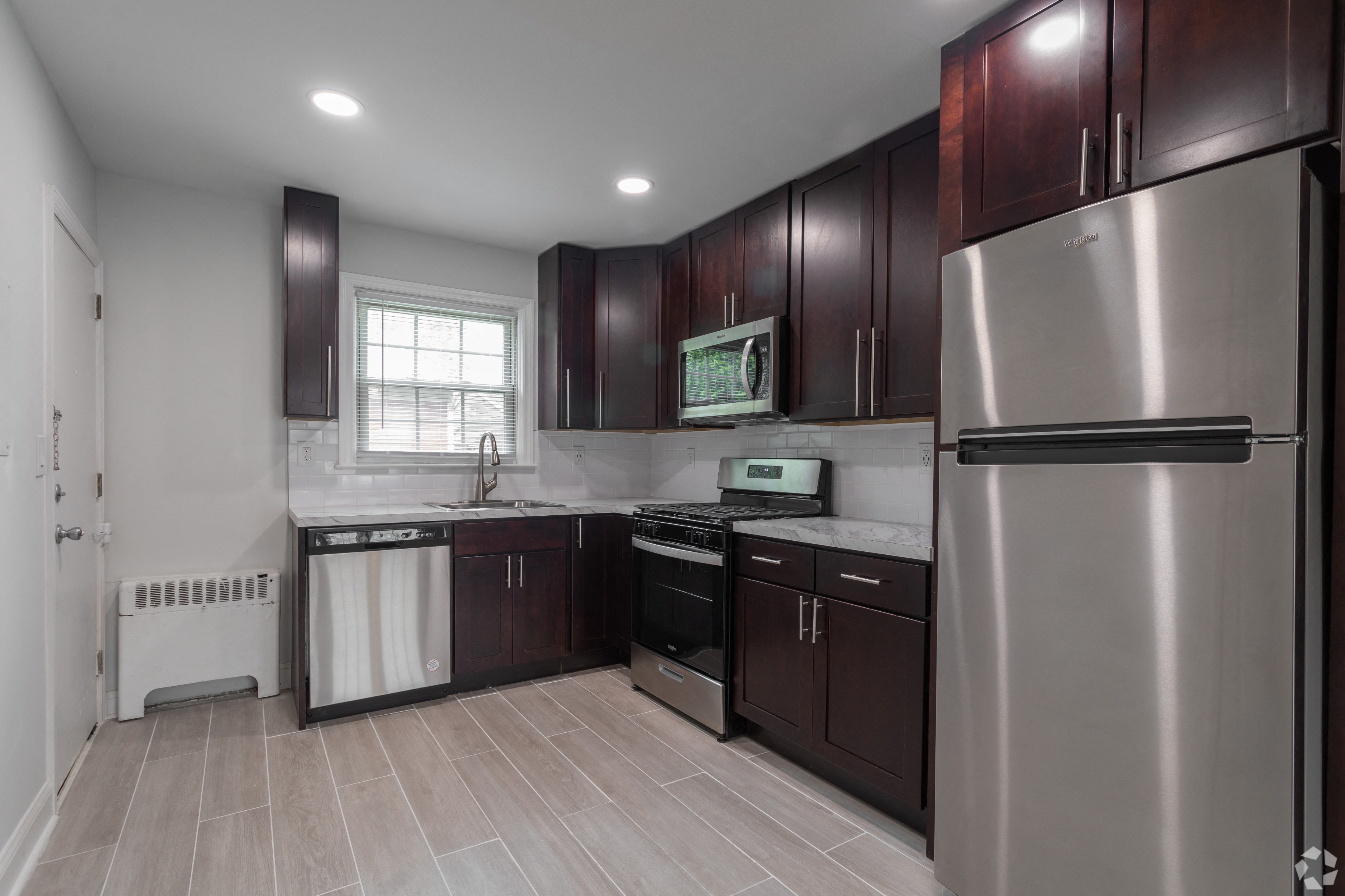 an empty kitchen with stainless steel appliances and dark wood cabinets