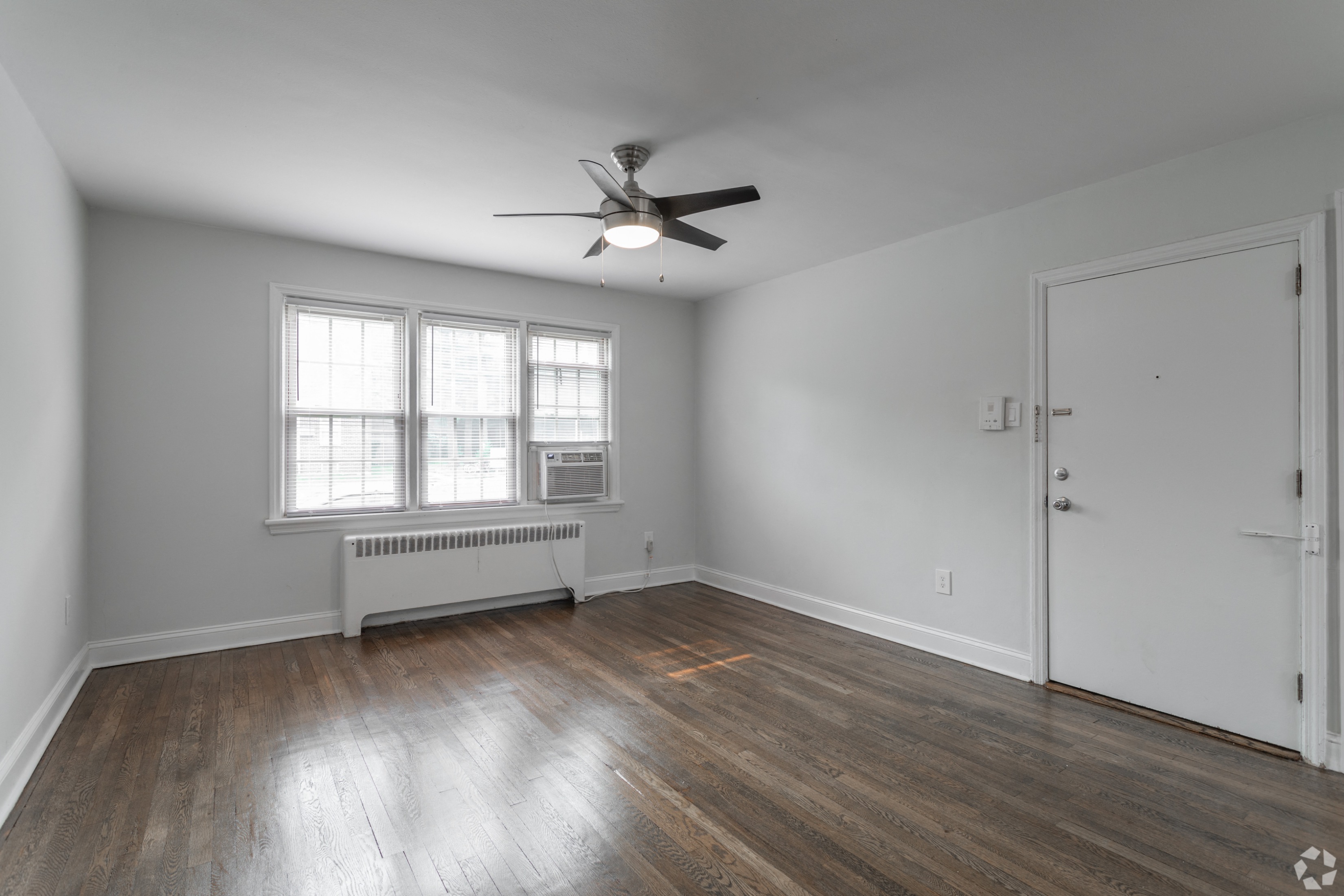 an empty living room with white walls and a ceiling fan