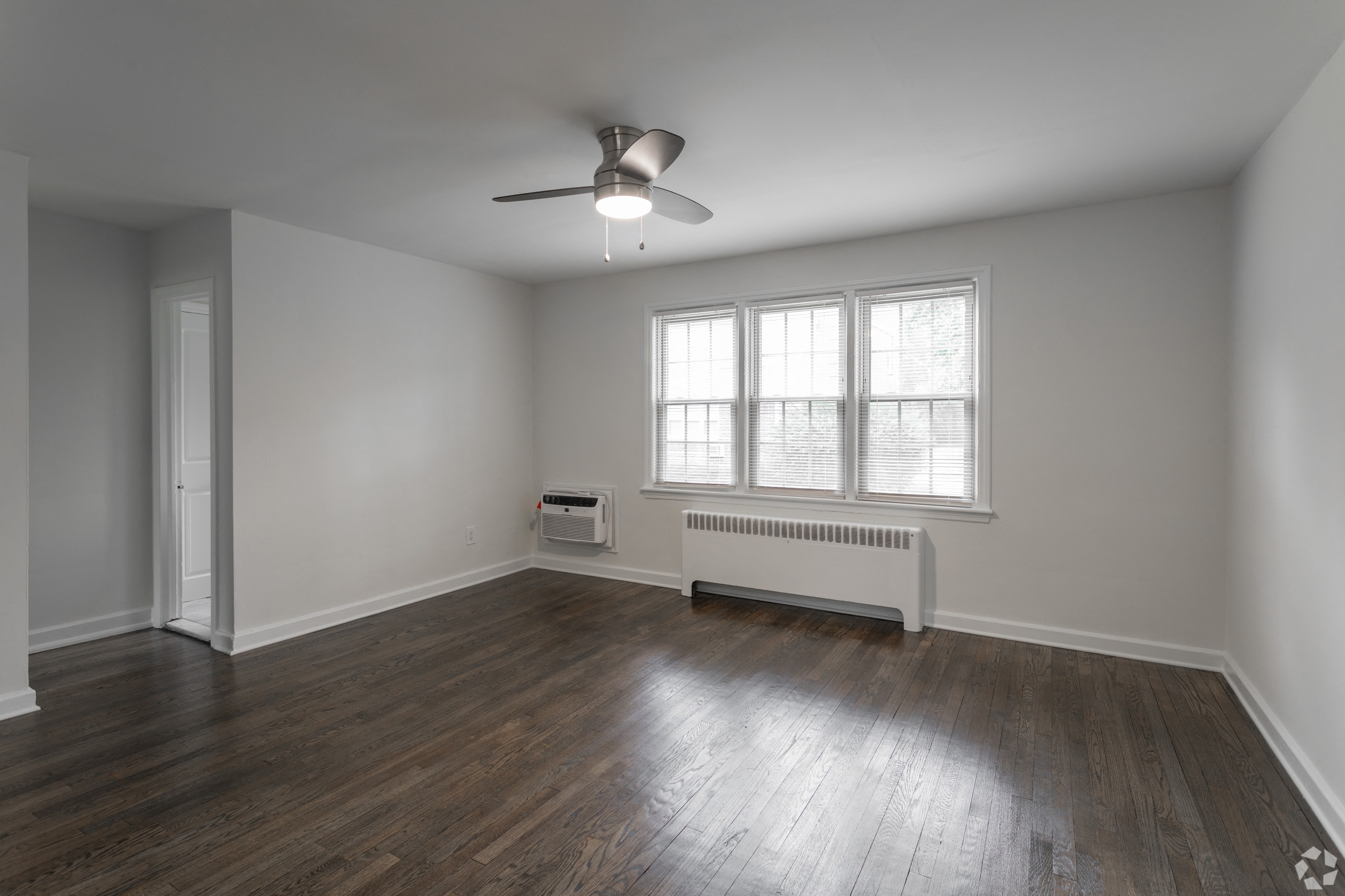an empty living room with wood floors and a ceiling fan