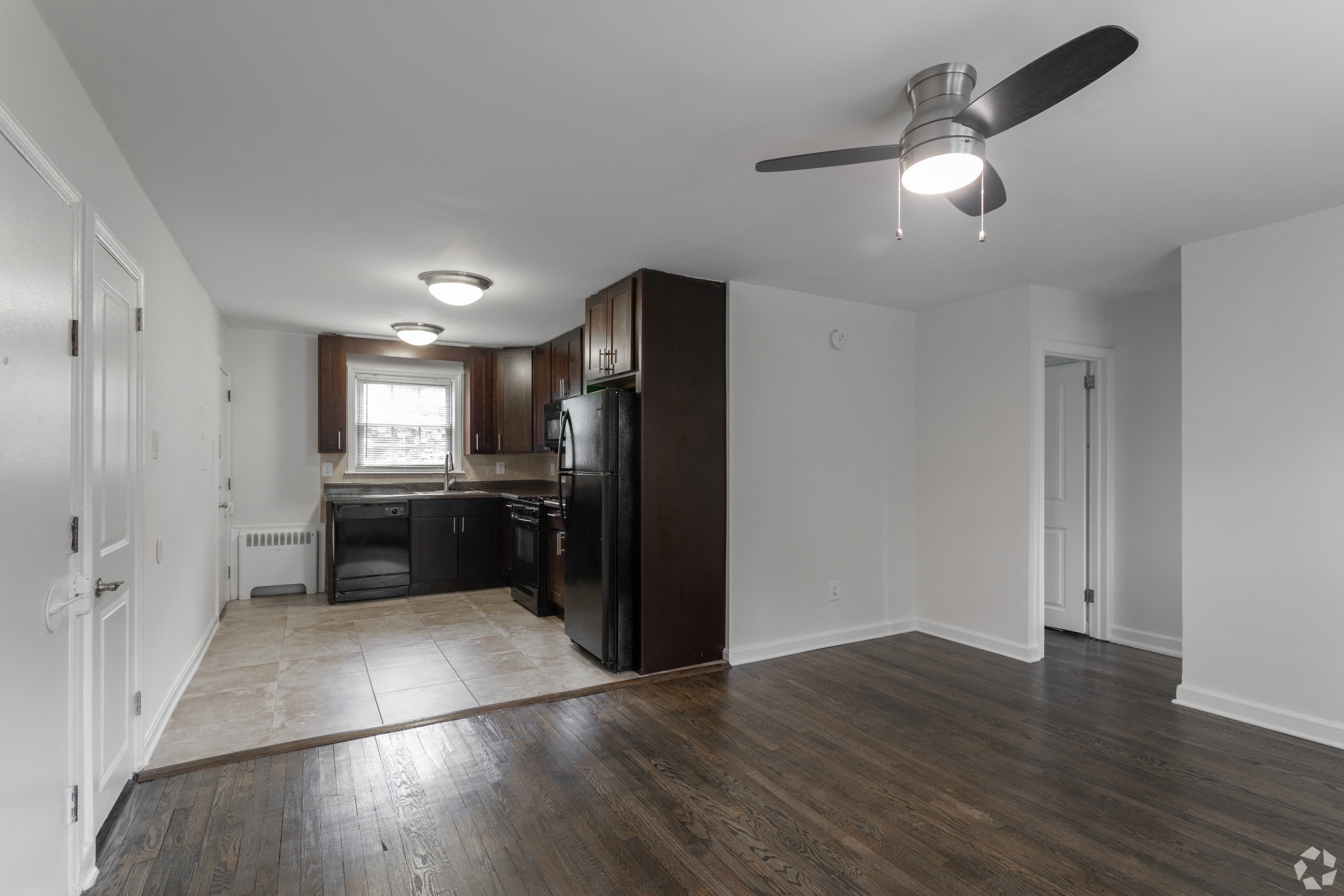 an empty living room and kitchen with a ceiling fan