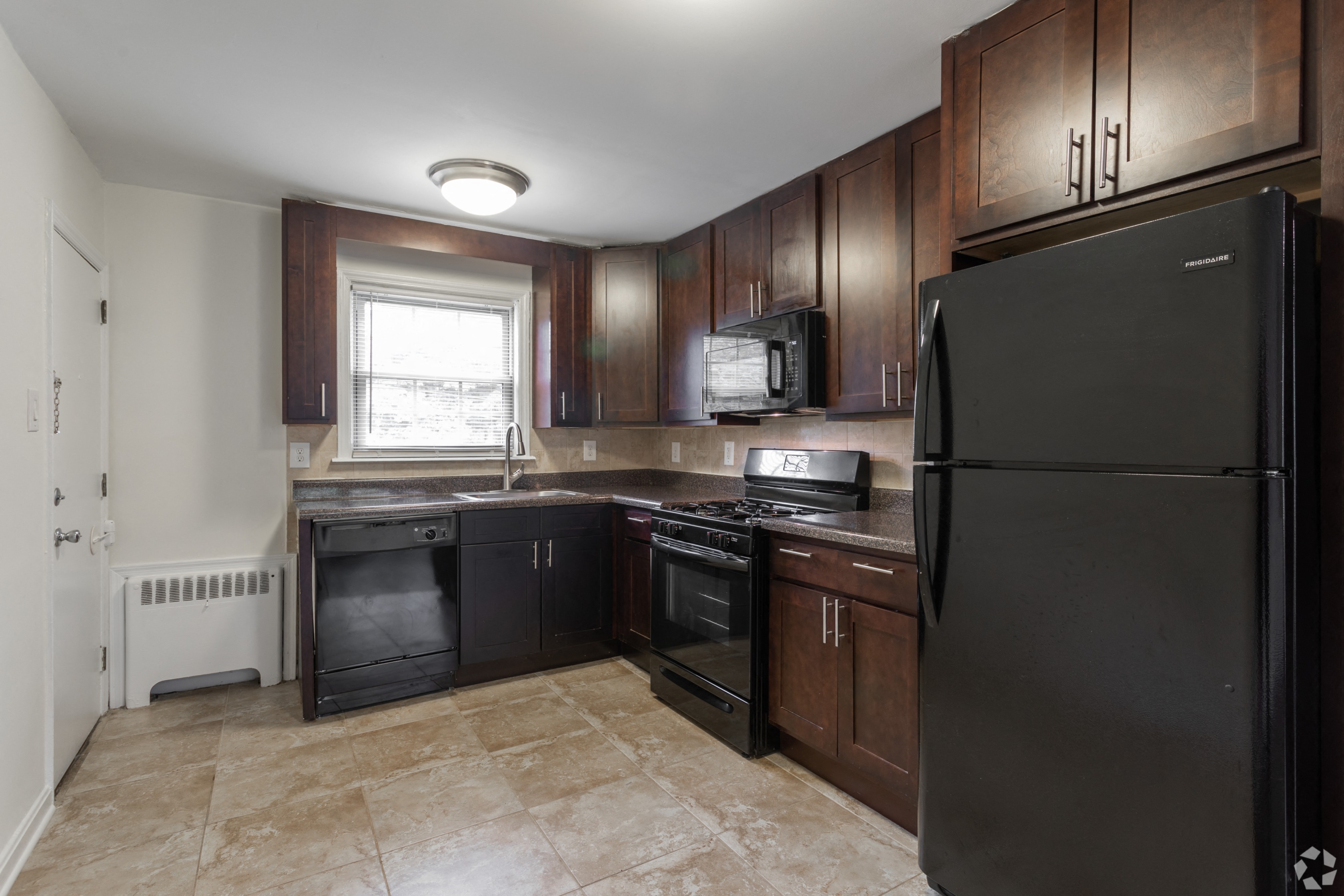 an empty kitchen with black appliances and wooden cabinets