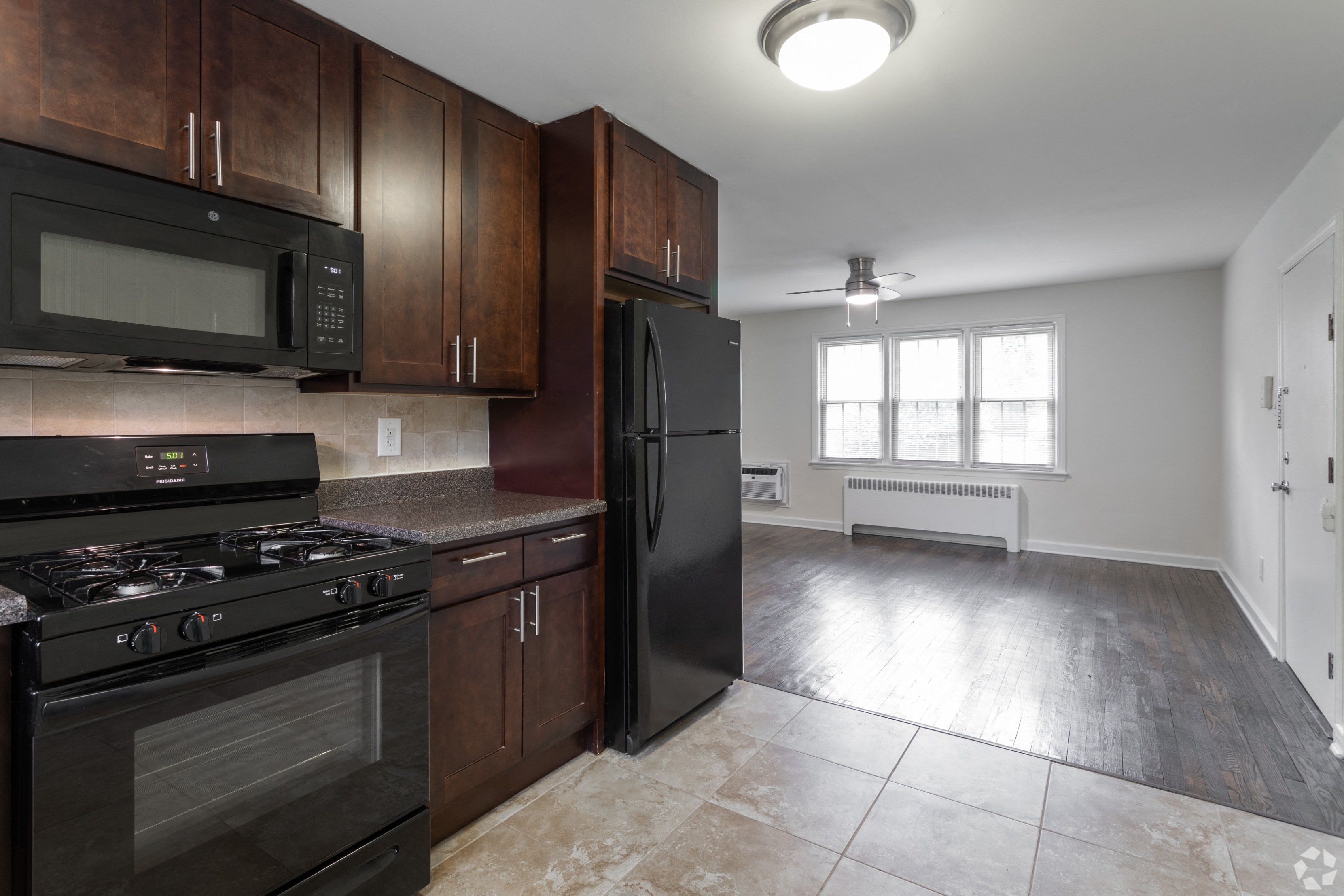 an empty kitchen with black appliances and wooden cabinets