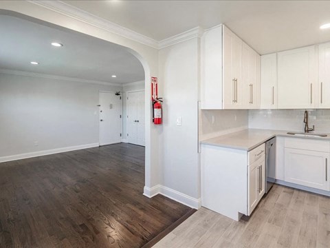 an empty kitchen with white cabinets and a wood floor