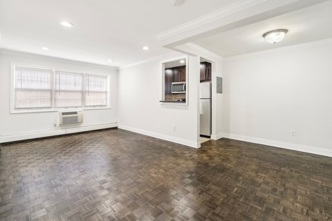 an empty living room with a refrigerator and a window