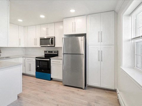 a kitchen with white cabinets and a stainless steel refrigerator