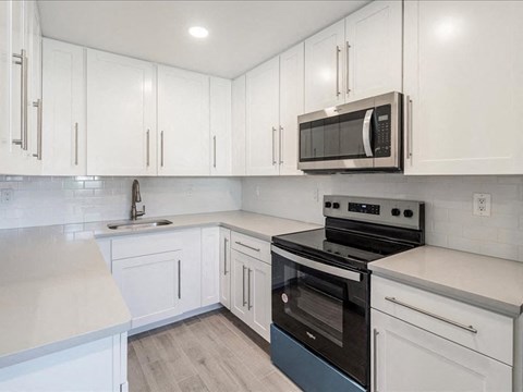 a white kitchen with a stove and a microwave